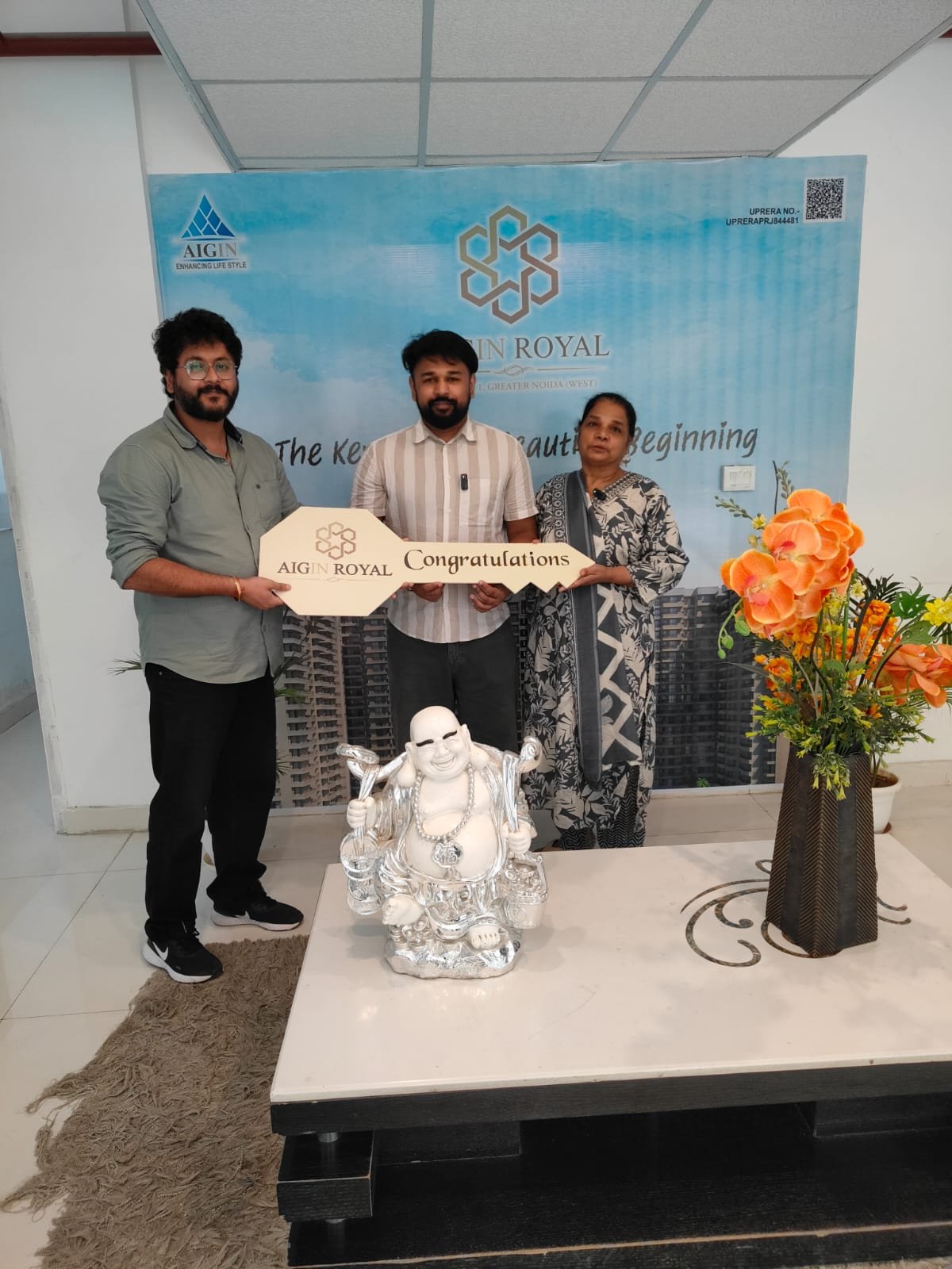 A family holding the AIGIN Royal congratulations key at their flat handover